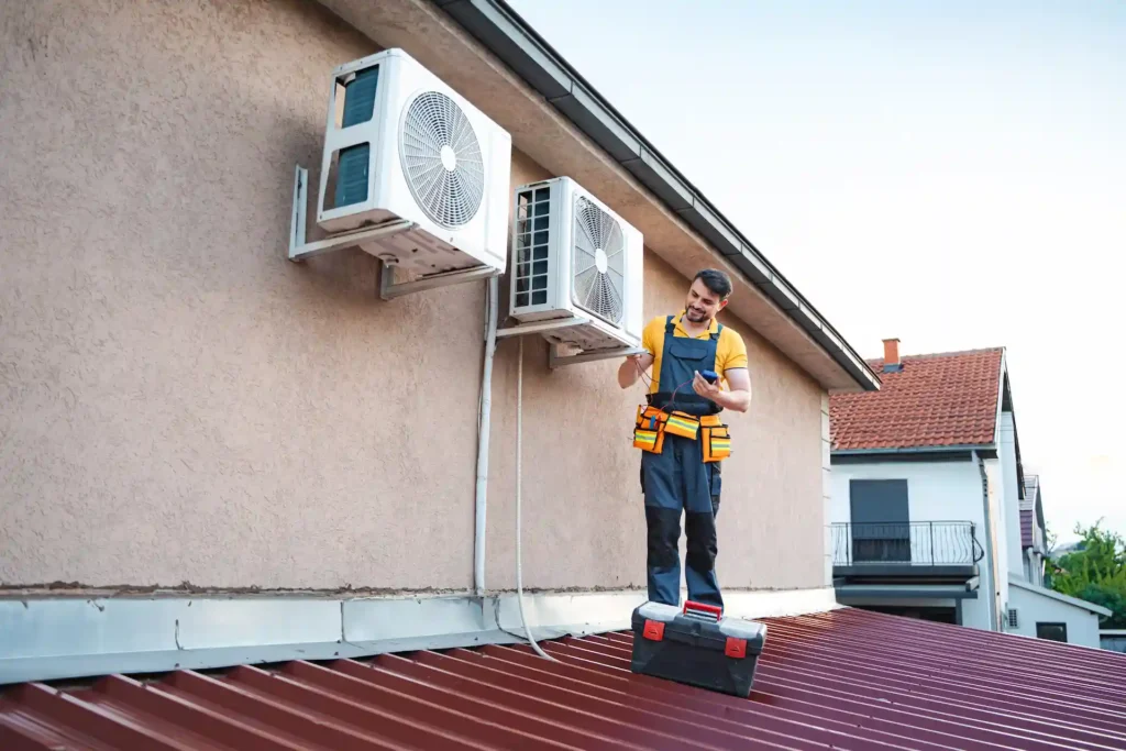 Technician installing air conditioning units on a roof